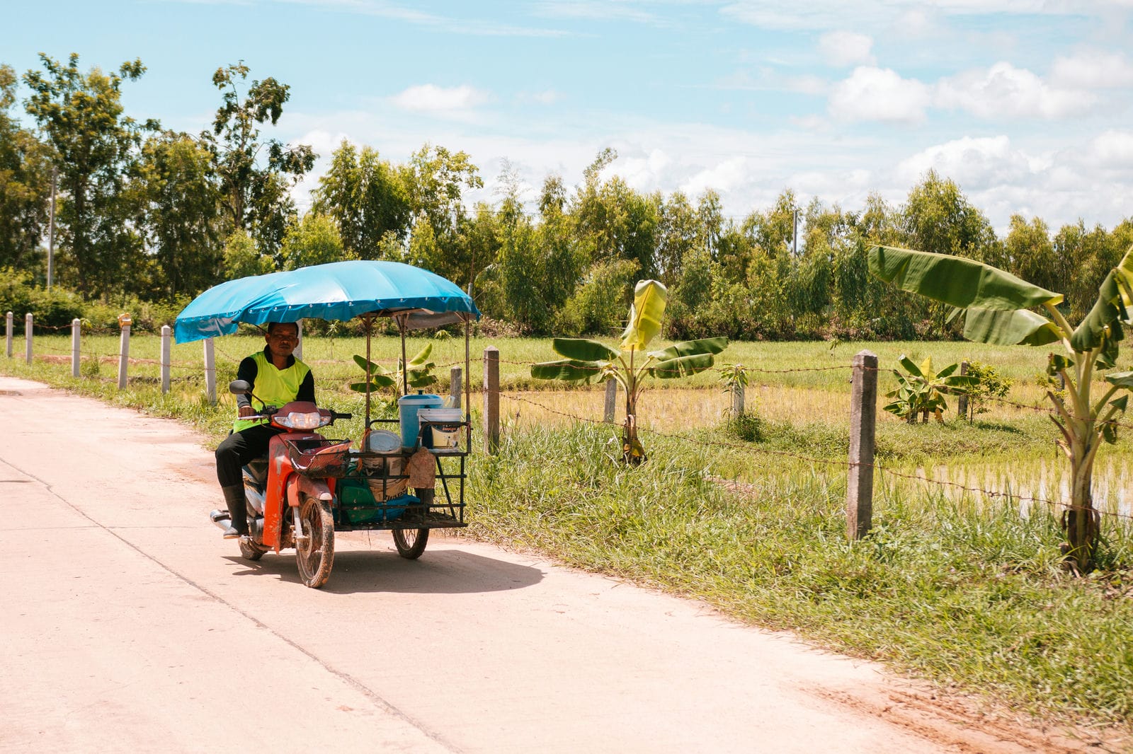 Thaise man rijdt langs de rijstvelden