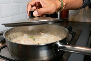 De groene curry met kabeljauw stooft zachtjes gaar.